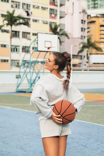 Young stylish woman  is posing on the Choi Hung Estate Basketball Court in Hong Kong city - Photo, Image