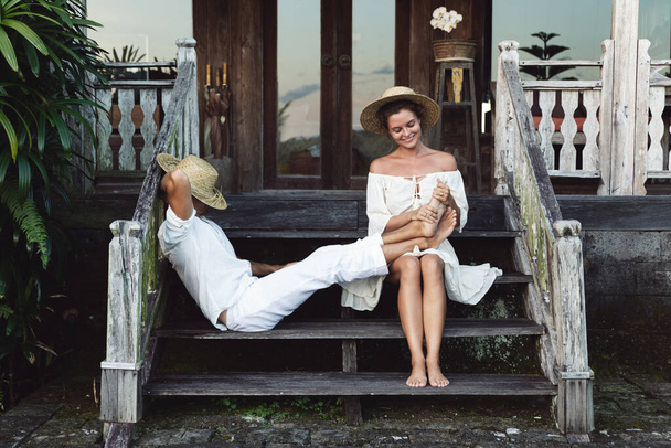 Young lovely couple wearing natural clothes are sitting on the stairs of the porch - Foto, Bild
