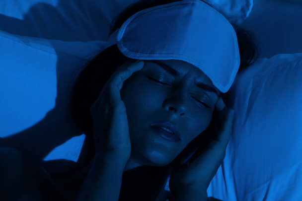 Young woman with a headache and insomnia in the dark bedroom - Фото, изображение