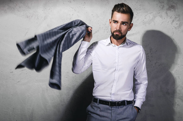 Handsome bearded man wearing gray suit is posing against concrete wall - Foto, Bild