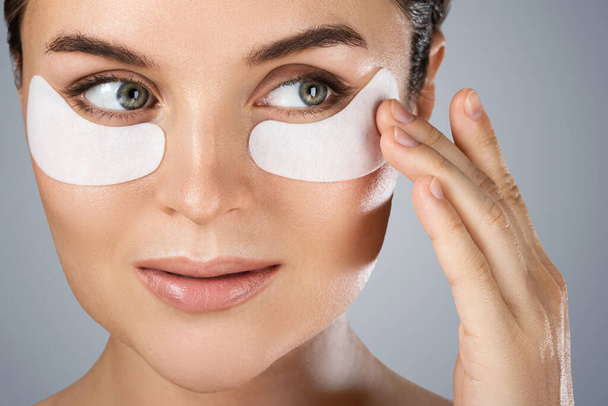 Young and beautiful woman with hydrating eye patches under her eyes o - Zdjęcie, obraz