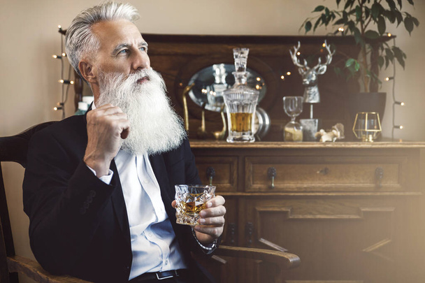 Stylish and handsome bearded senior man  with a glass of whiskey - Zdjęcie, obraz