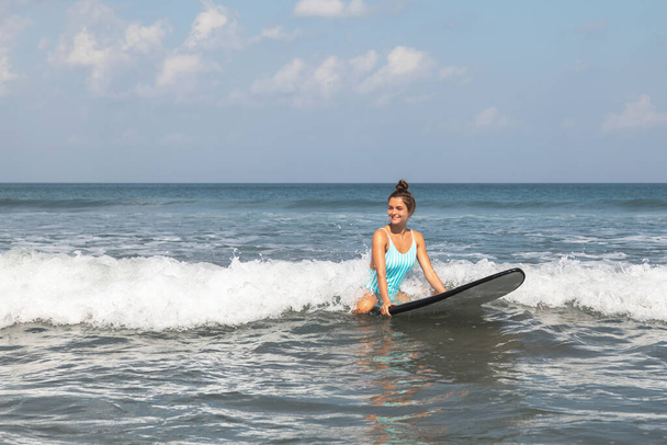 Young woman surfer is sitting on long board and  trying to catch the wave  - Fotografie, Obrázek