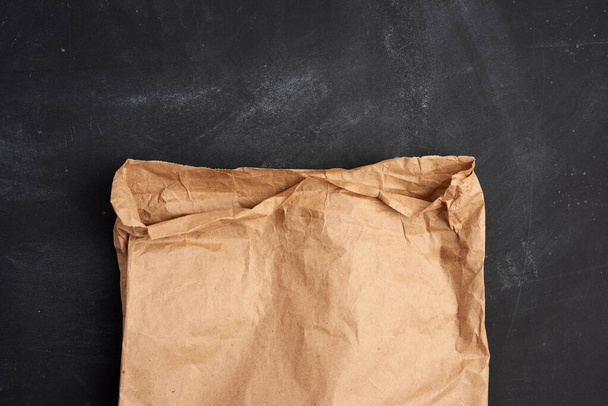 brown paper bag on a black background, top view, place for an inscription - Foto, Imagem