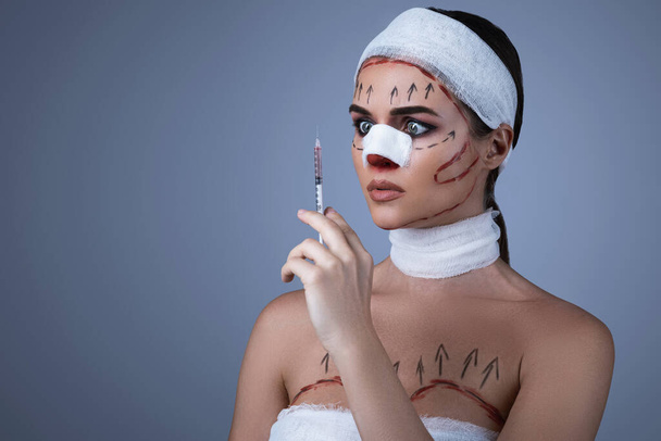 Conceptual image of plastic surgery victims. Woman wrapped with bandages and scars  is prepared for another one operation. - Zdjęcie, obraz