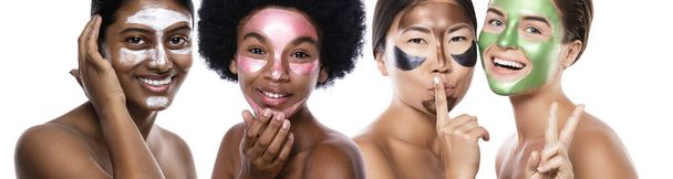 Beautiful multi-ethnic group of girls with colorful peel-off masks on their faces posing on white background - Φωτογραφία, εικόνα