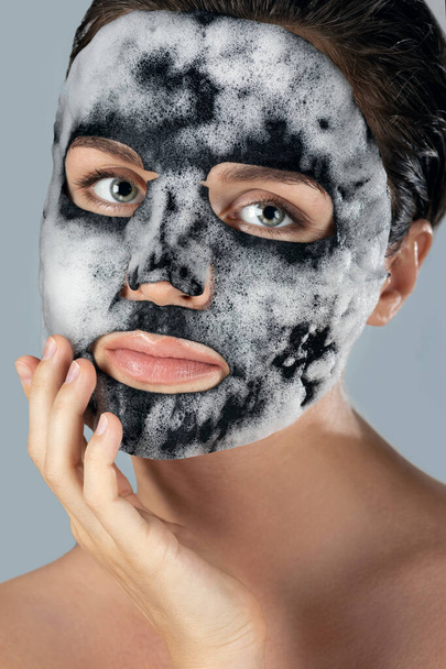 Young woman with  bubble sheet mask on her face on gray background - Zdjęcie, obraz