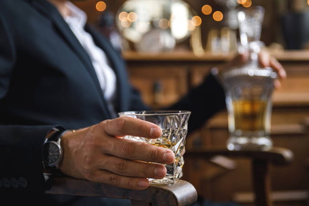 Primer plano de la mano masculina con un vaso de whisky caro
 - Foto, imagen