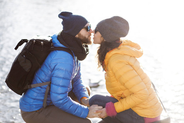 かわいい若い陽気なカップル-ボーイフレンドとガールフレンドは、公園を歩いて、色のジャケット、帽子とサングラスをかけて - 写真・画像