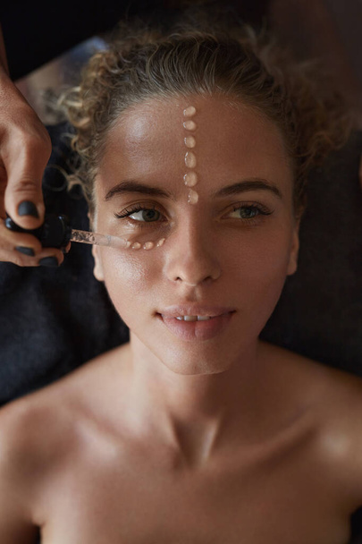 Spa Face Mask. Skin Care Beauty Treatment For Female. Beautician Applying Facial Oil Drops. Relaxed Woman On Natural Cosmetics Procedure. - Foto, Imagen