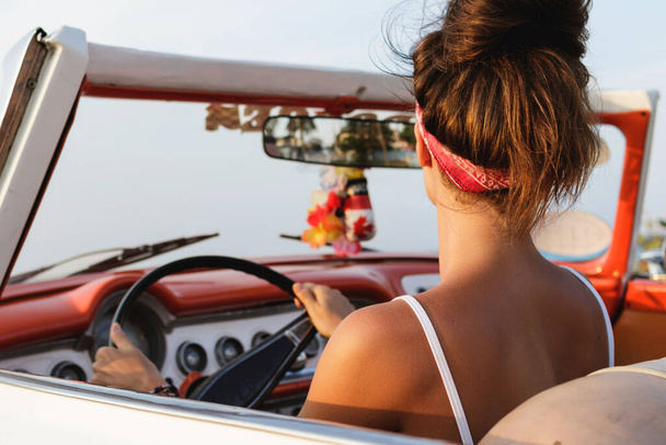Beautiful and happy woman is wearing bandana driving retro cabriolet car - Foto, Imagen