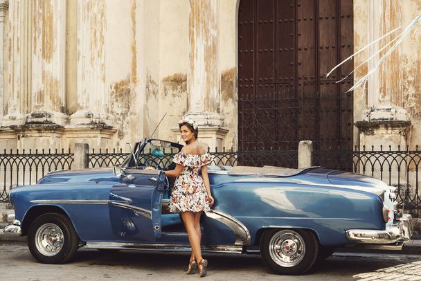Woman wearing beautiful dress and retro convertible car at Havana city - Фото, изображение