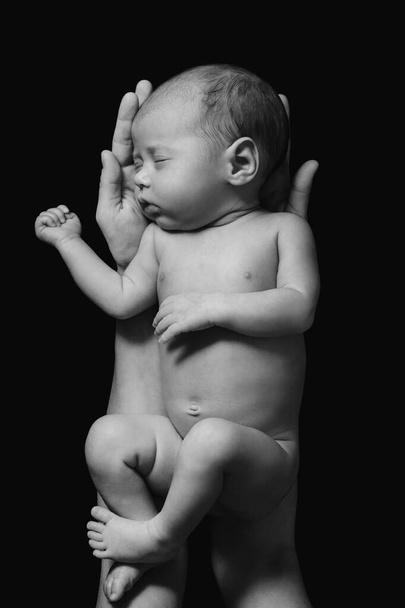 Cute newborn baby in the mother's hands on black background - Foto, Imagen