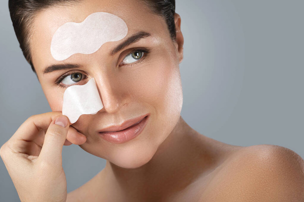 Young and beautiful woman with a cleansing pore strips on her face - Zdjęcie, obraz