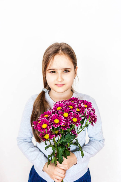 Girl with long hair in a gray blouse with a bouquet of pink red flowers, chrysanthemums, garden, flower and child, beauty, fashion, gift, mother's day, birthday - Foto, afbeelding