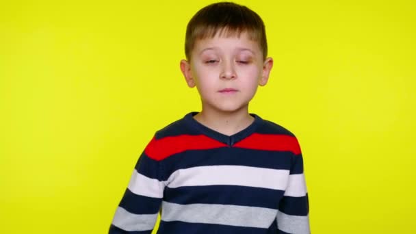 Μικρό αγόρι είναι έκπληκτος κλείνοντας το στόμα του με την παλάμη σε κίτρινο φόντο - Πλάνα, βίντεο