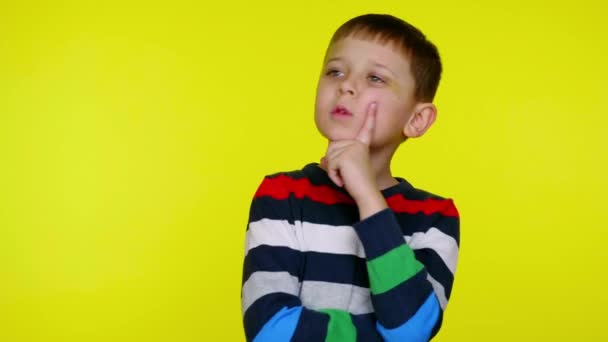 Confused child with index finger on cheek looks around and thinks what to choose - Footage, Video
