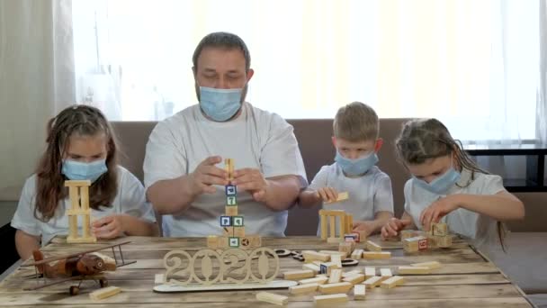 Papa en kinderen spelen met houten speelgoed en puzzels in de kamer. Sociale afstand en zelfisolatie in quarantaine tijdens de COVID-19 pandemie. - Video