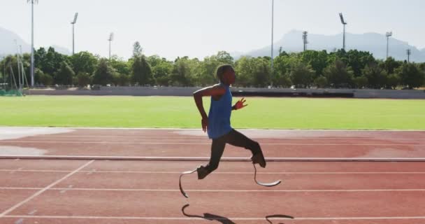Fit, disabled mixed race man with prosthetic legs running on race track in slow motion - Video, Çekim