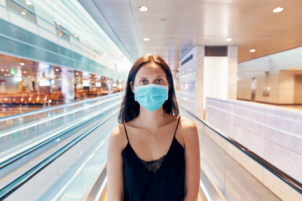 Woman in protection face mask posing in modern shopping mall or airport - Фото, изображение