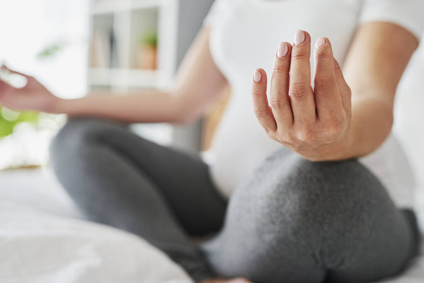 Pregnant woman meditating while sitting on bed - Photo, Image