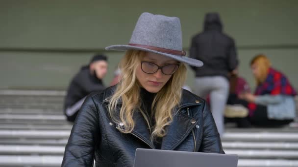 Detailní záběr blond vlasy studentka pracující s notebookem, psaní její bakalářské práce mimo - Záběry, video