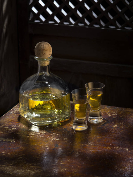 Close up view of bottle of tequila anejo and glasses on color background - Foto, afbeelding