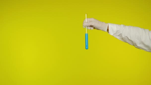 Mão na proteção luva de látex mostra um tubo de vidro com a substância azul claro
 - Filmagem, Vídeo