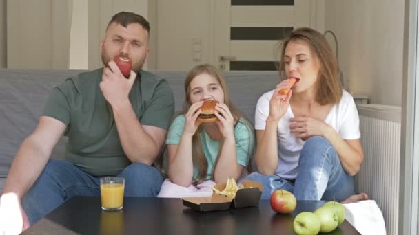 A fiatal, háromtagú család vacsorázik. Apa és anya vegetáriánus kaját esznek. A tinilány szereti a gyorskaját. Egészséges és egészségtelen táplálkozás. - Felvétel, videó