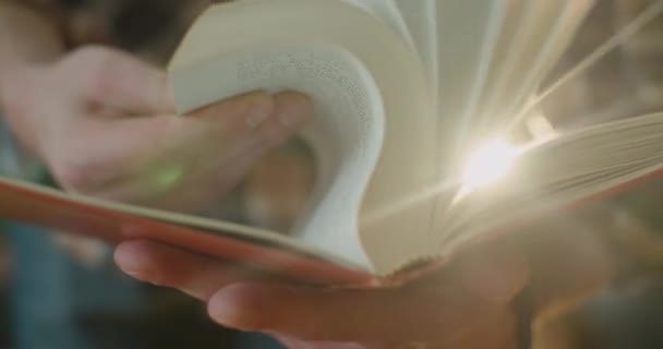 In Großaufnahme blättern Hände in einem alten Buch und Staub davon fliegt ans Licht. 4K - Filmmaterial, Video