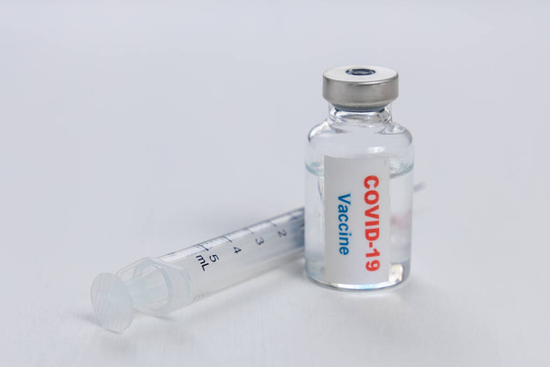 Beyaz zemin üzerinde Covid-19 veya coronavirus aşı şişesi ve şırınga - Fotoğraf, Görsel