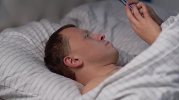 Мужчина пользуется мобильным телефоном перед сном
. - Кадры, видео