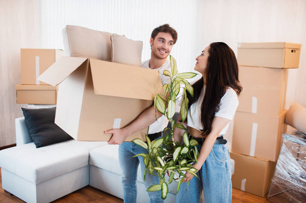 Happy couple with cardboard boxes in new house at moving day. - Photo, Image