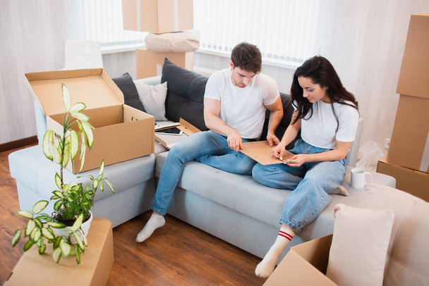 Happy young couple unpacking or packing boxes and moving into a new home. - Foto, afbeelding