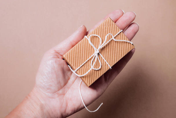 Aranyos kis hullámos ajándék doboz természetes húr a női kézben - Fotó, kép