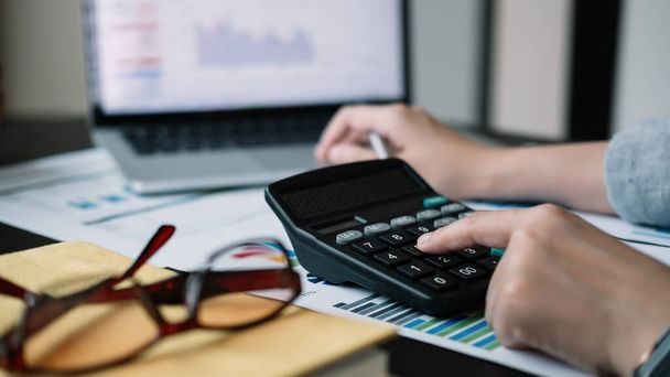Bedrijfsvrouw rekenmachine en laptop voor de berekening van financiën, belastingen, boekhouding, statistieken en analytisch onderzoek concept - Foto, afbeelding