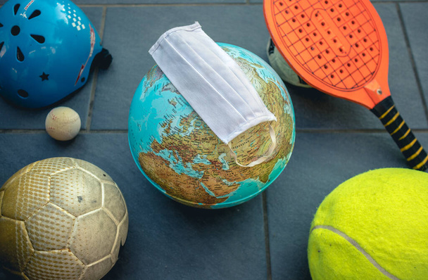 voetbal, tennis en honkbal ballen met een wereld in het midden en een masker - Foto, afbeelding