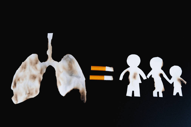 Paper cut of family members destroyed by cigarette on black background. Smoking destroying family concept. Quit smoking for life on world tobacco day. - Photo, Image