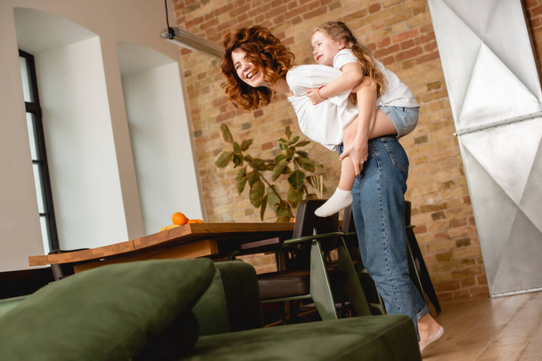 curly mother piggybacking cute daughter  - Valokuva, kuva
