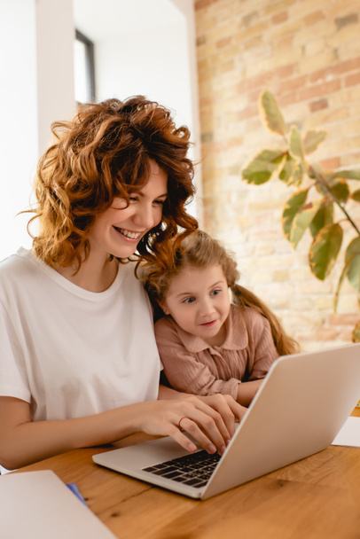 happy kid looking at laptop while freelancer mother working from home  - Zdjęcie, obraz