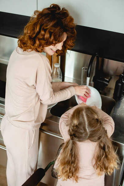 вид сзади на детскую стиральную тарелку со счастливой мамой
  - Фото, изображение