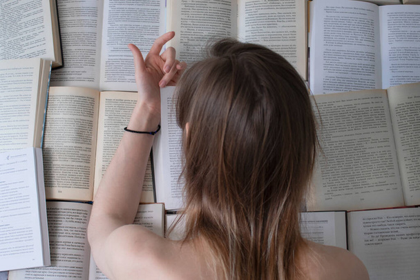 félmeztelen vékony lány fekszik nyitott könyveken - olvasás. otthon tanul - Fotó, kép