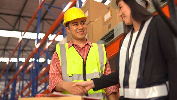 warehouse workers shaking hand in distribution warehouse. - Zdjęcie, obraz