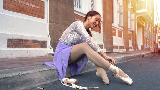 Nuori kaunis ballerina laittaa pointe kengät pitkin katua Thaimaassa
 - Valokuva, kuva