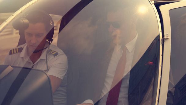 Üzletember és pilóta kis magánhelikopteren egy leszállóhelyen - Fotó, kép