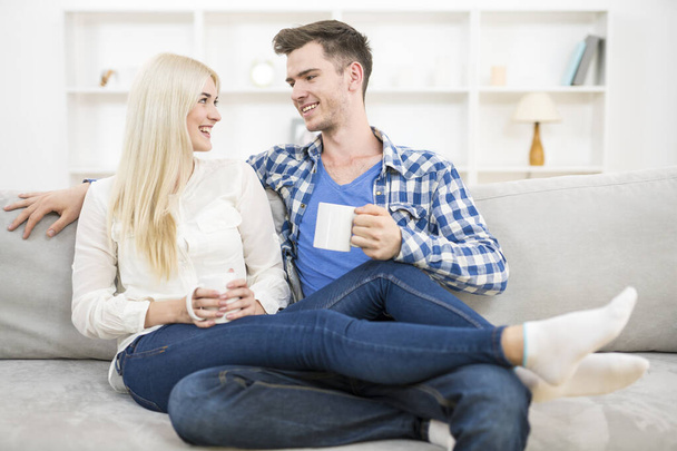 Счастливая пара с чашкой отдыха на диване
 - Фото, изображение