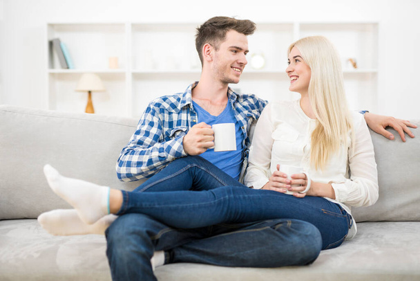La feliz pareja con una taza relajarse en el sofá
 - Foto, imagen