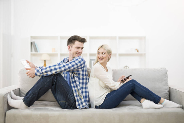 Щасливий чоловік і жінка з телефоном і планшетом сидять на дивані
 - Фото, зображення