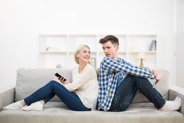 Glückliche Männer und Frauen mit Telefon und Tablet sitzen auf dem Sofa - Foto, Bild