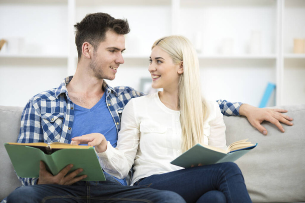The happy man and woman reading books on the sofa - Photo, Image